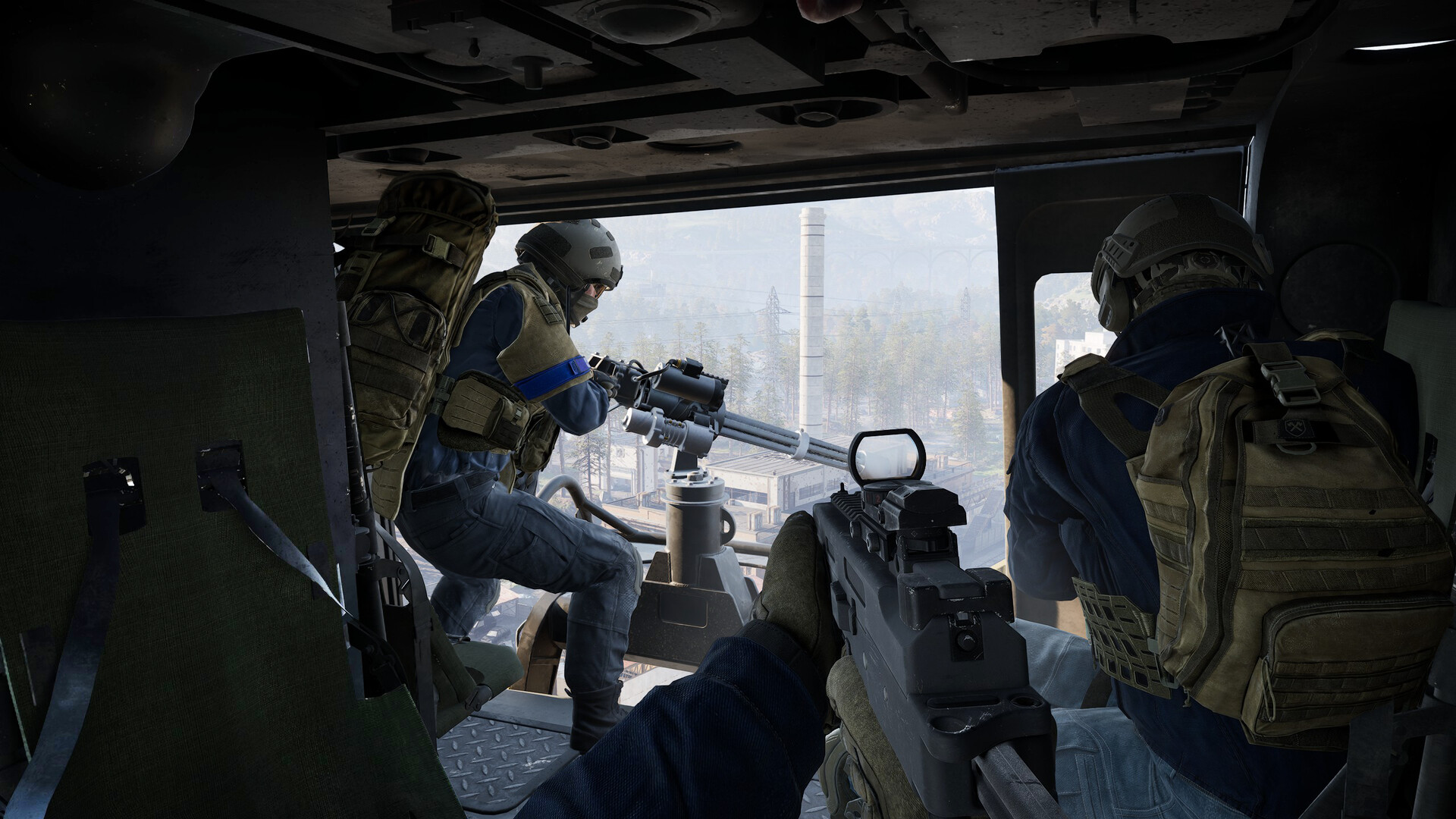 Official WARDOGS screenshot from inside a helicopter cabin, with a soldier manning a door-mounted machine gun above an industrial valley